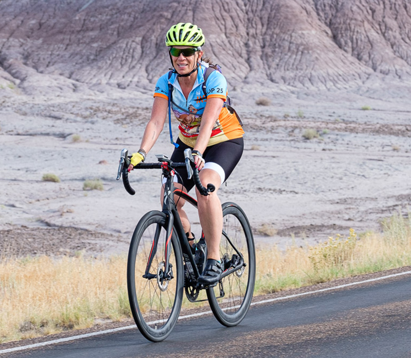 Joanie riding a road bike in a desert background